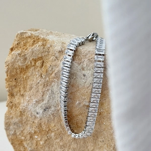 Bracciale tennis argento con zirconi rettangolari appeso a una pietra naturale grezza