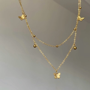 Collier double rang en acier titane doré avec pendentifs papillons et petites perles