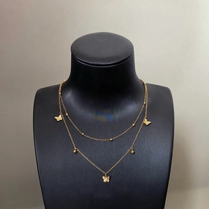 Collier double épaisseur avec pendentifs papillons dorés sur support à bijoux