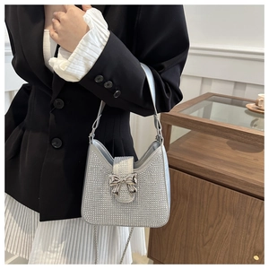 Détail du sac hobo argenté avec strass brillants et nœud en métal sur le rabat