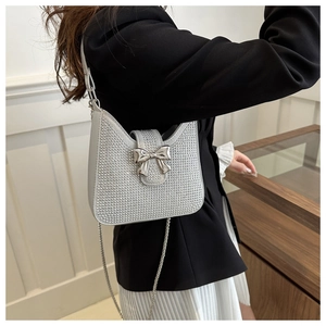 Détail d'un sac de soirée argenté en strass avec boucle nœud et bandoulière chaîne