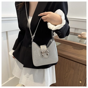 Détail du sac à main argenté avec strass et nœud papillon porté par un mannequin