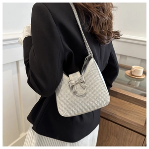 Détail de sac bandoulière argenté serti de strass avec nœud métallique et chaîne