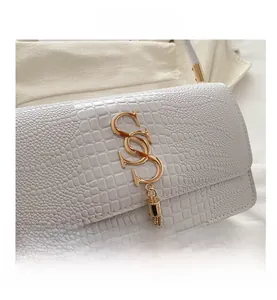 Close-up of white crocodile pattern leather texture with golden letter S buckle and tassel