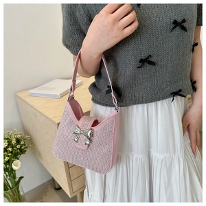 Détail du sac à bandoulière rose en strass avec nœud argenté et bandoulière chaîne