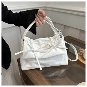 Sac cabas blanc en cuir PU avec nœud décoratif et bandoulière posé sur une table en bois