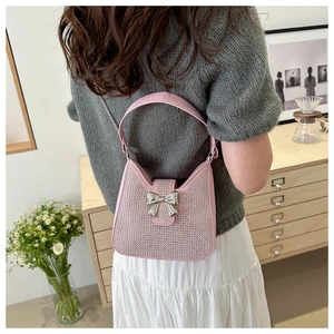 Détail d'un sac bandoulière rose en strass avec un nœud argenté sur un mannequin