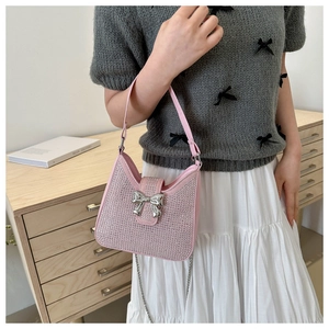 Gros plan du sac à main rose en strass avec fermoir nœud argenté et chaîne élégante