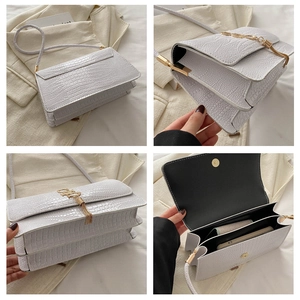 Detail view of white crocodile pattern shoulder bag featuring golden tassel and internal pockets