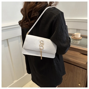 Detail of white crocodile embossed shoulder bag with gold metal logo and fringe tassel