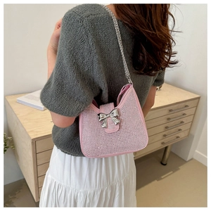 Détail du sac bandoulière rose en strass avec nœud argenté et chaîne élégante sur un modèle