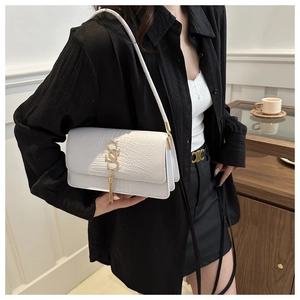 Detail of white crocodile texture underarm bag with gold S-buckle and tassel pendant