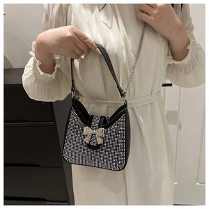 Détail du sac en similicuir noir avec strass brillants et nœud en métal argenté