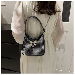 Détail du sac à main brillant avec nœud en strass, chaîne argentée et bandoulière cuir