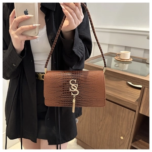 Close-up of brown crocodile pattern handbag with golden S logo and metallic fringe details