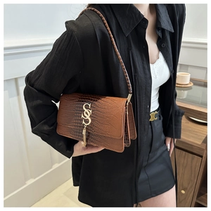 Detail of crocodile embossed leather bag with golden S-shaped buckle and fringe tassels