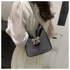 Sac à main noir à strass avec chaîne argentée et fermoir nœud porté par le modèle
