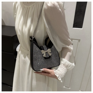Détail d'un sac bandoulière noir avec strass argentés et une boucle de nœud