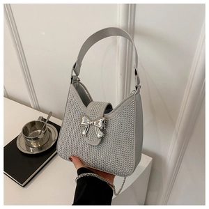 Détail d'un sac à main en strass argentés avec nœud métallique et bandoulière chaîne