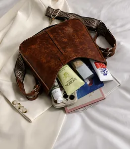 Detailansicht braune PU-Tasche mit gewebtem Trageriemen und geräumigem Innenfach für Zubehör