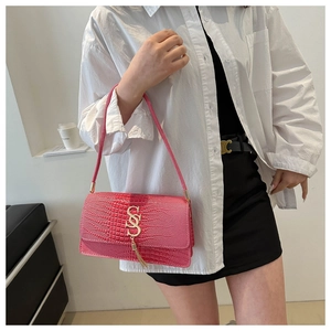 Detail of fuchsia crocodile texture handbag featuring golden SS metal buckle and tassel