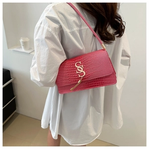 Detail of rose red faux crocodile skin underarm bag with gold logo and tassel accent