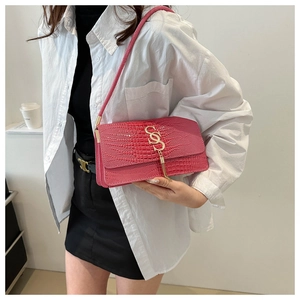 Detail of hot pink crocodile textured shoulder bag with gold double-S clasp and tassel