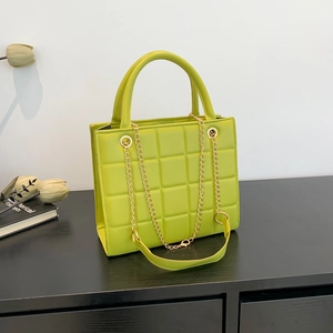 Grass green quilted square handbag with gold chain strap and top handle on black wood surface
