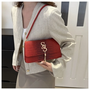 Detail of red crocodile pattern bag featuring gold SS logo and elegant chain tassel
