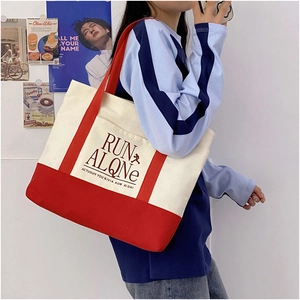 Detail of red and white canvas tote bag featuring front pocket and vintage printed art