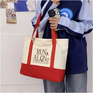 Detail of contrast color canvas tote bag with red handles and Run Alone printed text