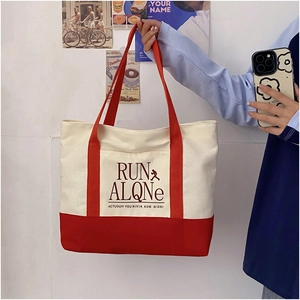 Detail of red and cream contrast canvas tote bag featuring RUN ALQNe graphic print