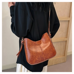 Braune Vintage Schultertasche aus Ölwachsleder in der Seitenansicht am Model