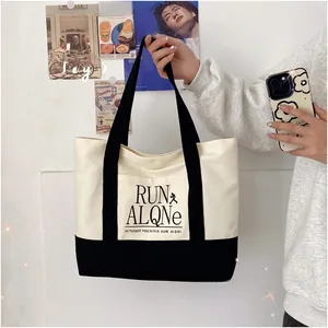 Close-up of contrast canvas tote bag featuring RUN ALONE lettering and black webbing straps