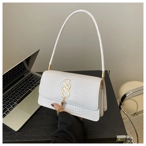 Detailed view of white crocodile pattern texture with golden logo and tassel on handbag