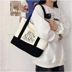 Detail shot of a large contrast canvas tote bag with black straps and letter print