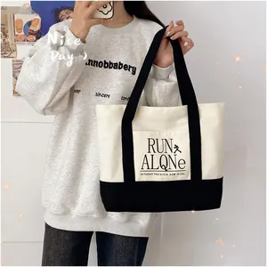 Detail of high-capacity contrast canvas tote bag with Run Alone print on shoulder