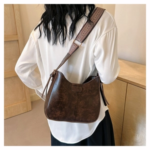 Detail der braunen Vintage-Kunstledertasche mit ethnisch gewebtem breitem Schultergurt