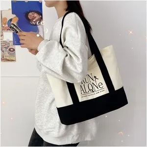 Detail of contrast canvas tote bag featuring RUN ALONE text and casual shoulder straps