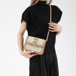 Woven contrast crossbody bag with leather trim and gold buckle on a black outfit