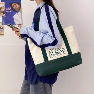 Detail of a large canvas tote bag with contrast stitching and artistic text on the side