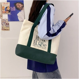 Detail of color block canvas tote bag showing the dark green strap and printed lettering