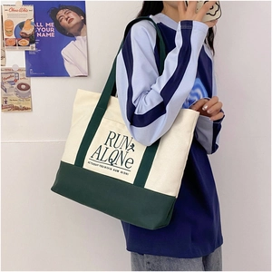 Detail of contrast canvas tote bag with Run Alone lettering and adjustable shoulder strap