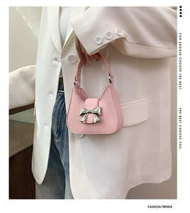 Detailed view of pink mini handbag with silver bow charm and matching handle strap