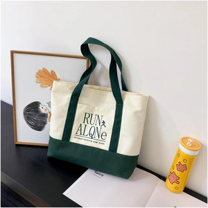 Detail of canvas tote bag in off-white and dark green with RUN ALQNe text design
