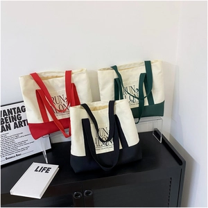 Three minimalist canvas tote bags in red, green, and black contrasting color designs