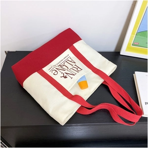 Detail of canvas tote bag showing red and cream contrast trim with text print