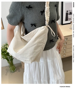 Detail of a beige tote bag with pleated cloud shoulder strap and adjustable drawstrings