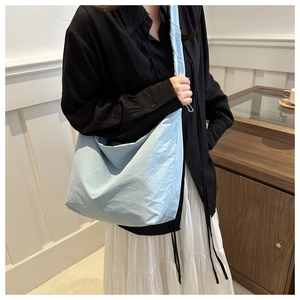 Light blue large capacity nylon tote bag with pleated strap worn by a female model