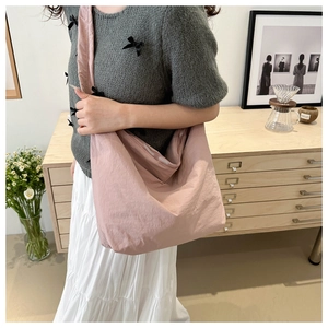 Detailed view of pink pleated canvas tote bag worn with a casual outfit in a cozy setting